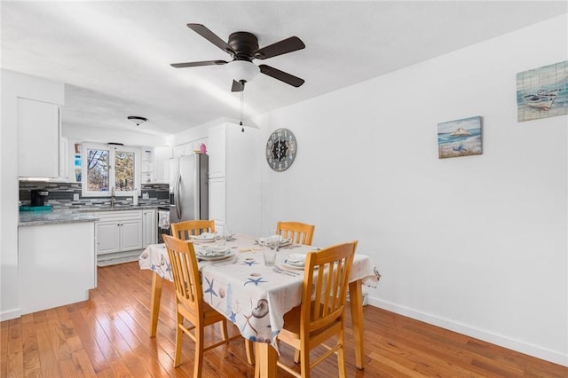 dining room with ceiling fan, light wood finished floors, and baseboards