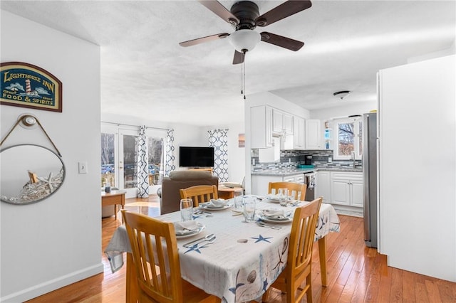 dining space featuring baseboards, a ceiling fan, and light wood-style floors