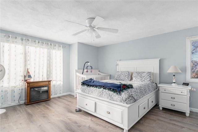 bedroom featuring multiple windows, baseboards, and wood finished floors