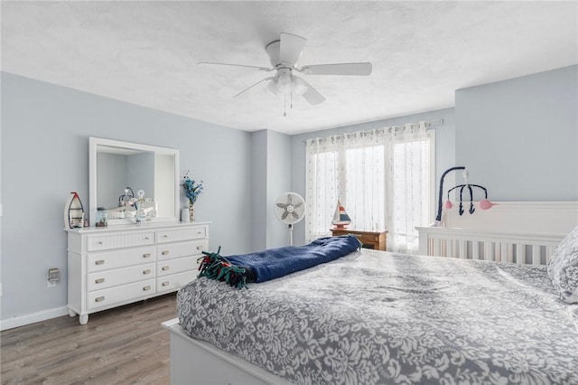 bedroom featuring a textured ceiling, wood finished floors, a ceiling fan, and baseboards