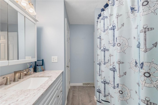 full bath with a shower with shower curtain, wood finished floors, vanity, visible vents, and baseboards