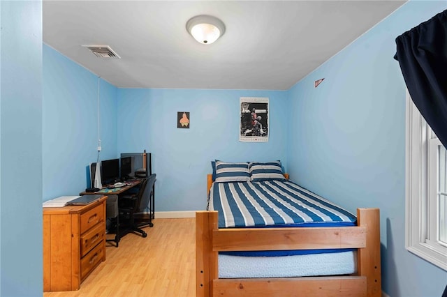 bedroom with baseboards, visible vents, and wood finished floors