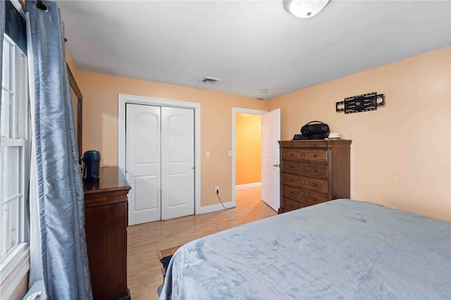 bedroom featuring light wood-style flooring, a closet, visible vents, and baseboards