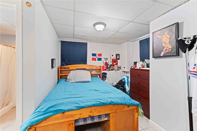 bedroom featuring a paneled ceiling and light tile patterned floors