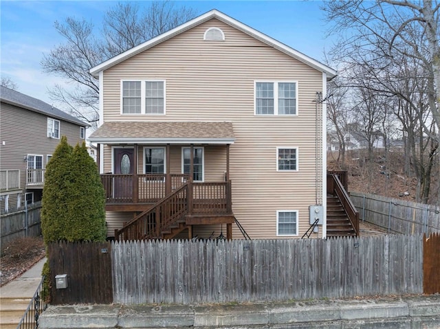 view of front of home featuring a fenced front yard, stairs, and roof with shingles