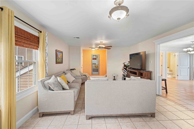 living area with ceiling fan with notable chandelier, visible vents, baseboards, and light tile patterned floors