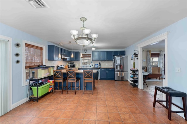 kitchen featuring a notable chandelier, visible vents, blue cabinetry, stainless steel refrigerator with ice dispenser, and tasteful backsplash