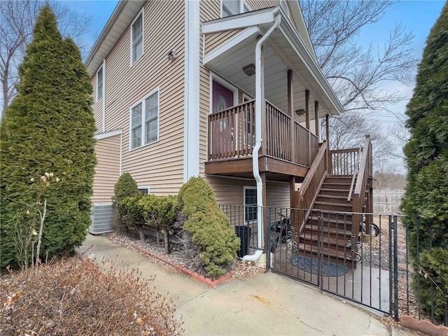 view of side of home featuring fence and stairs