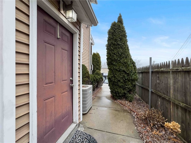 view of exterior entry featuring fence and central air condition unit