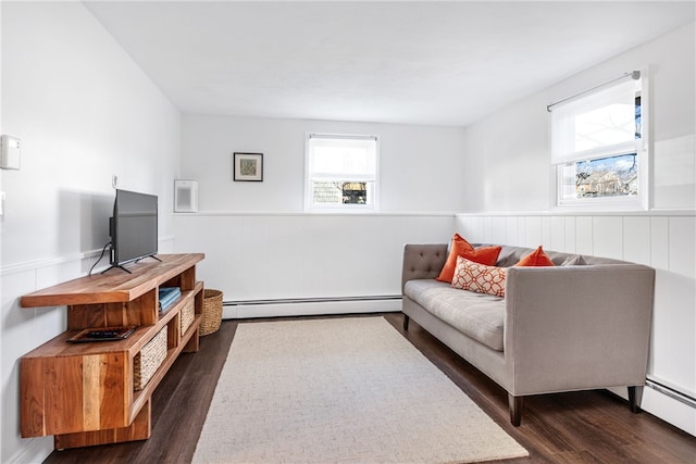 living room with dark wood finished floors, baseboard heating, plenty of natural light, and a wainscoted wall