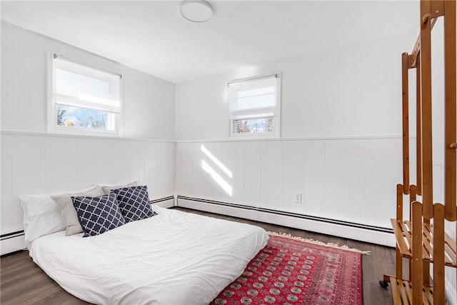 bedroom featuring a wainscoted wall, baseboard heating, and wood finished floors