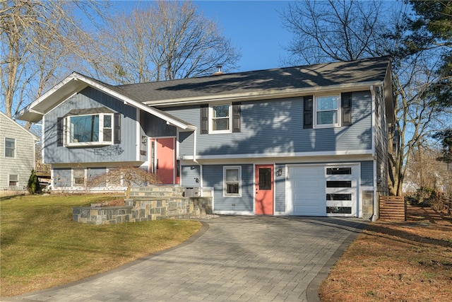 bi-level home featuring a garage, decorative driveway, and a front yard