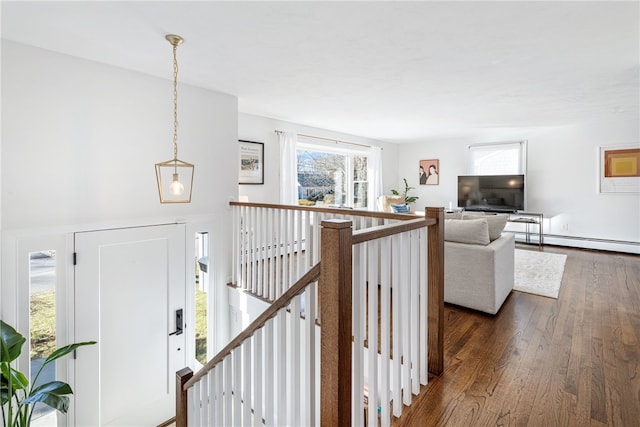 hallway featuring an upstairs landing, a baseboard heating unit, and dark wood-style flooring