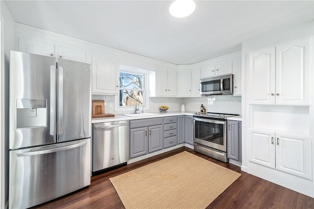 kitchen featuring a sink, stainless steel appliances, gray cabinets, and white cabinetry