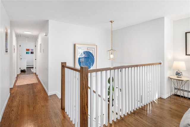 hallway with a baseboard heating unit, baseboards, attic access, an upstairs landing, and wood finished floors