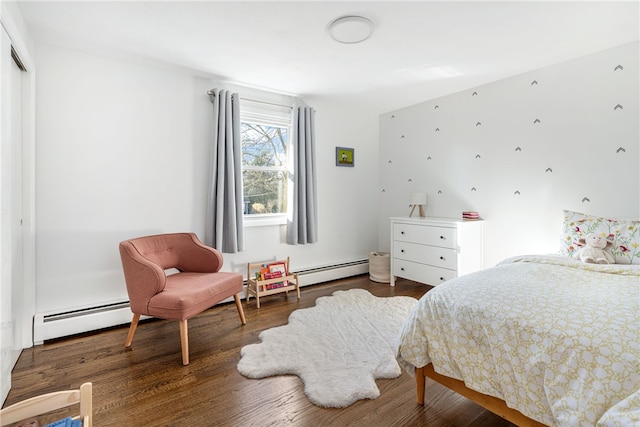 bedroom featuring a closet, baseboard heating, and wood finished floors