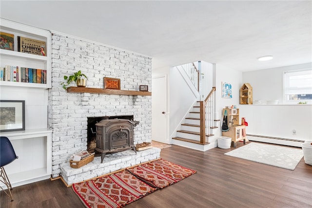 living room with a baseboard radiator, wood finished floors, a wood stove, and stairway