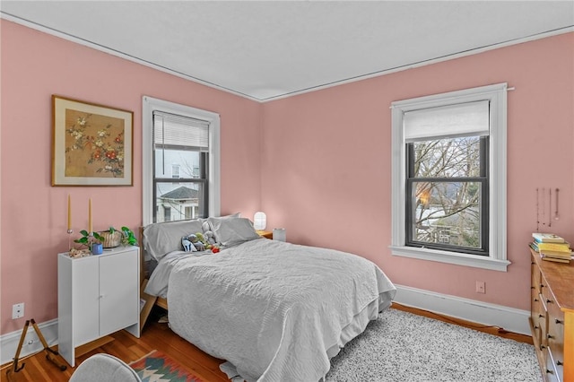 bedroom featuring multiple windows, wood finished floors, and baseboards