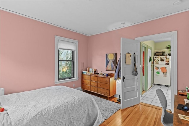 bedroom featuring light wood-type flooring and freestanding refrigerator