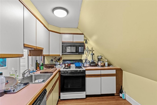 kitchen featuring black microwave, wood finished floors, a sink, white cabinetry, and gas range