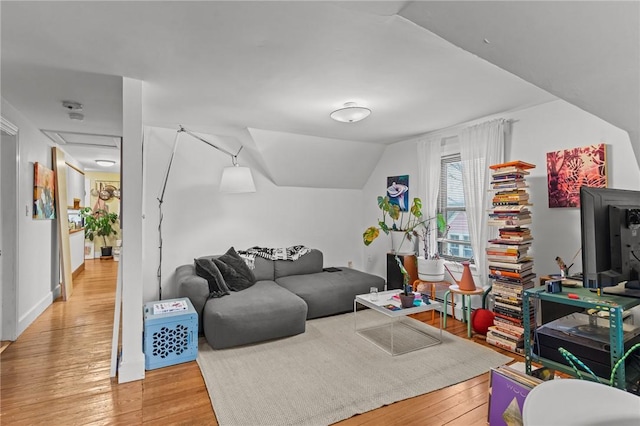 living area featuring vaulted ceiling, hardwood / wood-style floors, and attic access