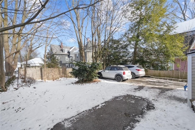 snowy yard with a residential view and fence