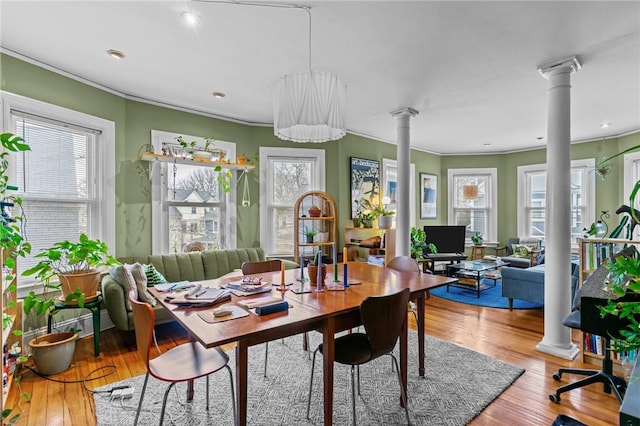 dining space featuring ornamental molding, ornate columns, and wood finished floors