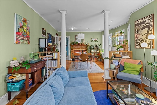 living room with ornamental molding, wood finished floors, decorative columns, and baseboards