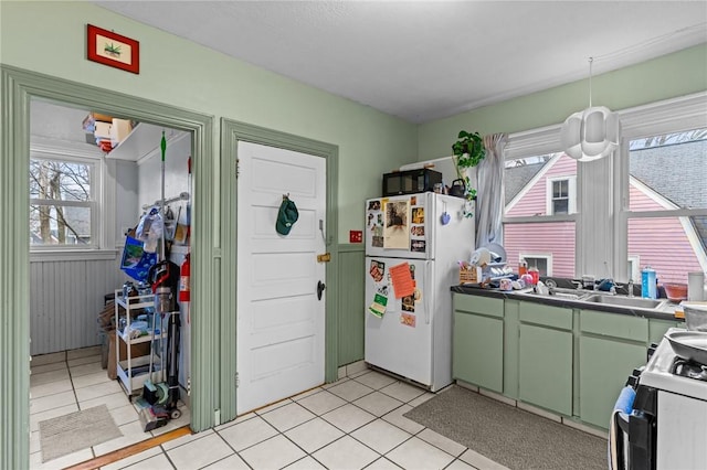 kitchen featuring light tile patterned floors, hanging light fixtures, white appliances, and green cabinetry