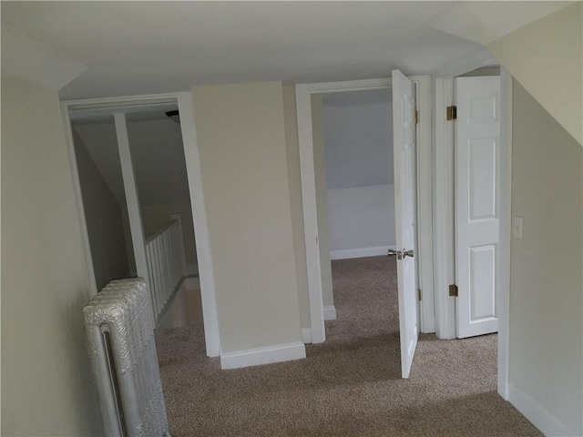 corridor with carpet, radiator, and baseboards