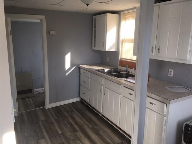 kitchen featuring baseboards, white cabinets, dark wood-style flooring, light countertops, and a sink