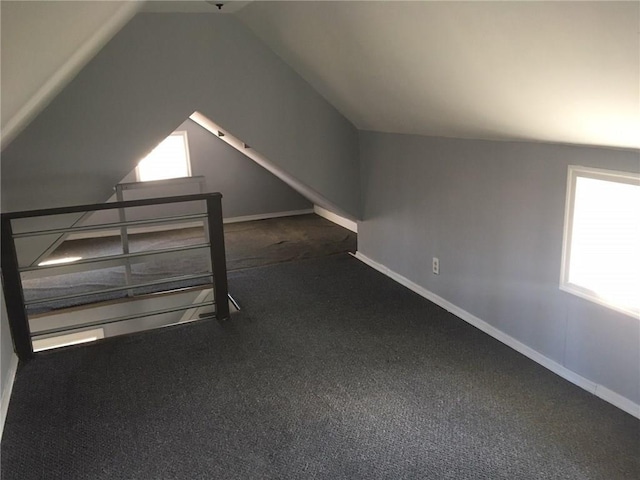 bonus room featuring vaulted ceiling, dark carpet, and baseboards