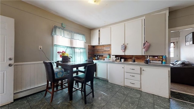 kitchen featuring a baseboard radiator, wood walls, white cabinets, light countertops, and wainscoting