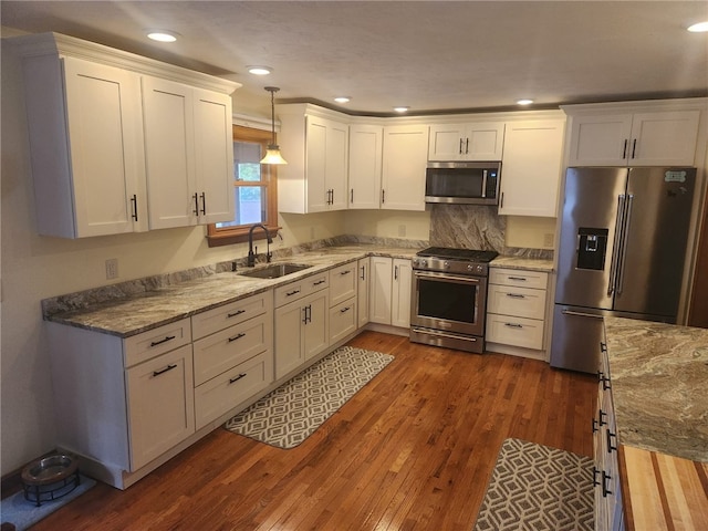 kitchen featuring dark wood-type flooring, a sink, white cabinetry, appliances with stainless steel finishes, and light stone countertops