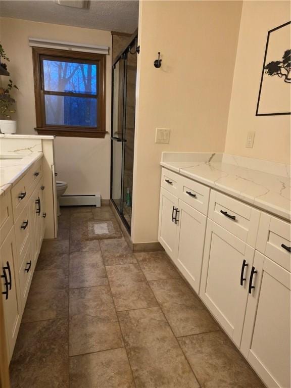 full bath with a baseboard heating unit, a stall shower, vanity, and toilet