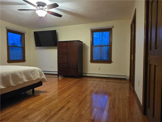 bedroom with a baseboard radiator, ceiling fan, and hardwood / wood-style floors