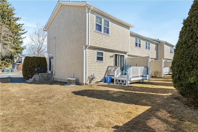 rear view of property with a lawn, a deck, and central AC