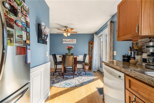 kitchen featuring visible vents, brown cabinetry, freestanding refrigerator, light wood-style floors, and white dishwasher