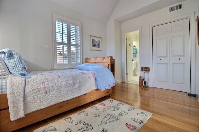 bedroom featuring lofted ceiling, a closet, visible vents, and wood finished floors