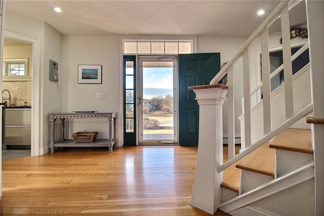 entryway with stairs, a baseboard heating unit, wood finished floors, and recessed lighting