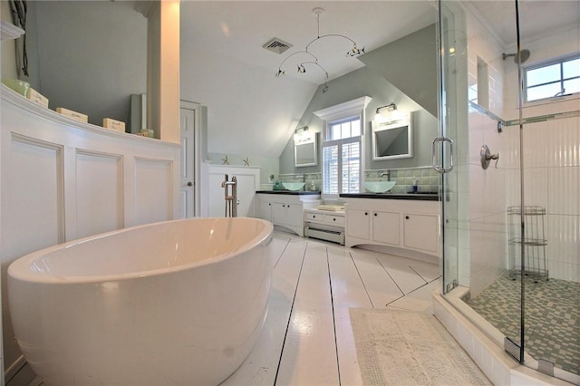 bathroom with a stall shower, visible vents, a soaking tub, vaulted ceiling, and vanity