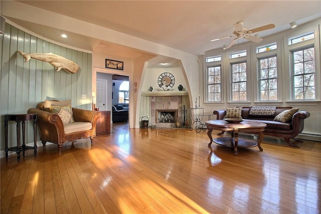 living area with a healthy amount of sunlight, hardwood / wood-style flooring, a fireplace, and a ceiling fan