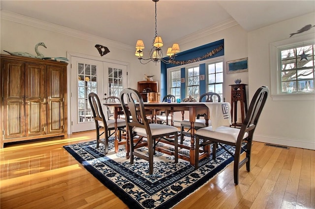 dining space with light wood finished floors, baseboards, visible vents, ornamental molding, and french doors