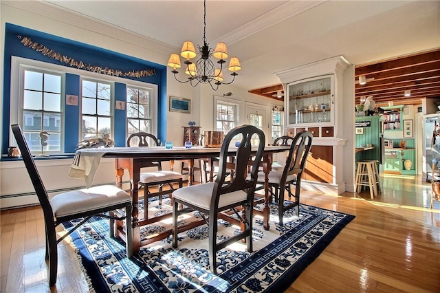 dining room featuring hardwood / wood-style floors, an inviting chandelier, and crown molding