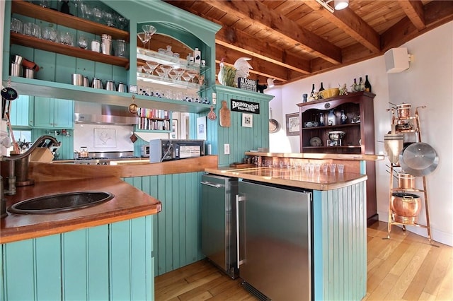 bar with light wood-style flooring, wood ceiling, stainless steel refrigerator, wet bar, and beamed ceiling