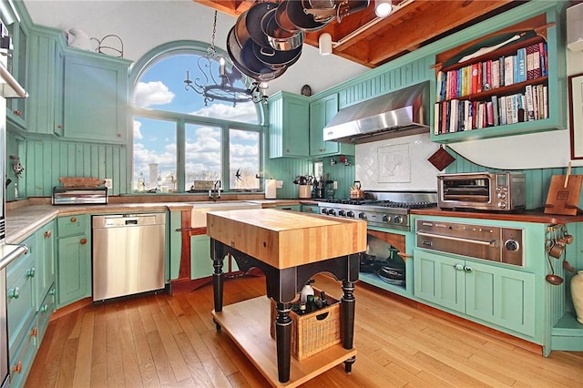 kitchen with a notable chandelier, a toaster, stainless steel appliances, exhaust hood, and light wood-type flooring