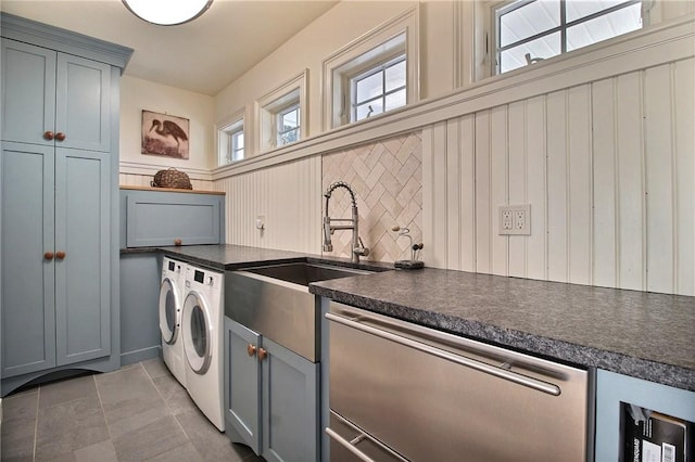 washroom featuring a wainscoted wall, light tile patterned floors, cabinet space, a sink, and washer and dryer