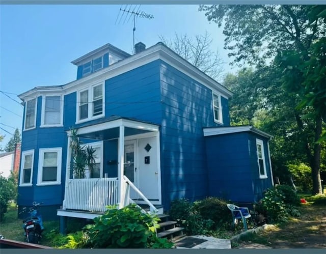 view of front of home with a chimney and a porch