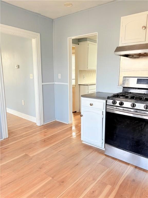 kitchen featuring white cabinets, under cabinet range hood, stainless steel gas range oven, and light wood-style flooring