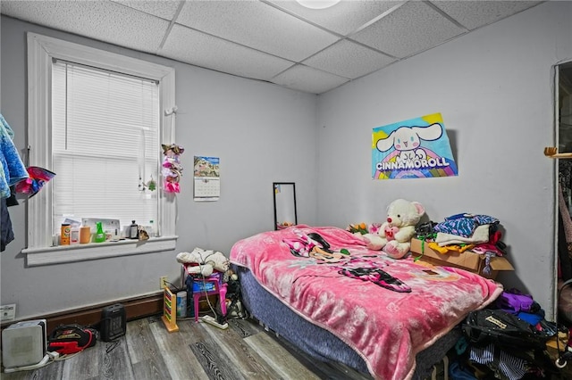 bedroom with wood finished floors and a paneled ceiling